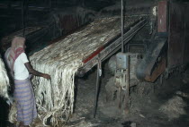 Male worker in Fort Gloster jute mill feeding raw jute on to machinery.Kolkata Calcutta