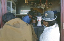 La Ceja.  Two women standing in front of hatmakers stall.