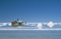 View over the white salt flats with salt piled up ready for collection by truck Lorry