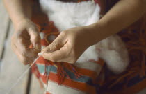 Member of Karen tribe spinning wool by hand.  Cropped view of hands and yarn.