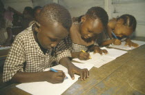 Primary school pupils writing at their desks.