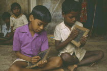 Tribal boys at rural school writing on slates.