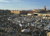 Djemaa El Fina Square. View over busy market square lots of people at stalls and buildings behind.Marrakesh Marrakech