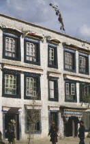 Traditional houses with ribbons hanging above the windows and people walking in the foreground