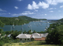 Ordnance Bay.  View over rooftops towards bay with moored yachts and surrounding tree covered coastline.