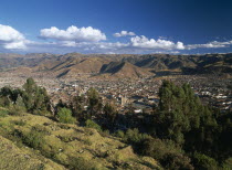 Hillside view over trees and Cusco to the mountains beyond.