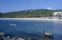 View of beach with people swimming and a canoe.