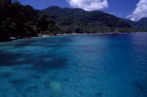 View from the sea toward the west coast of the island with green hills and boats in the distance