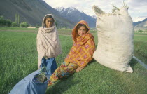 Ismaili girls sitting in fields with sacks. NWFP