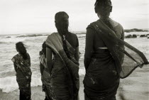 Orphanage workers enjoy a day out by the sea  backs to camera.Black and white image.