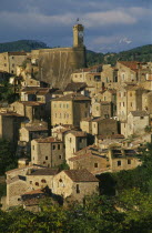 Etruscan town.  View over stone houses with tiled rooftops and clock tower behind.