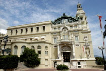 The Opera House entrance with lamp post, sign to the bar. Steps leading up to decorated door, statues, columns and balcony on the very decorative building.