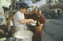 Giving early morning Alms to young Monks queuing up at side of road. Myanmar