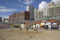 Young men playing Volleyball on the lower esplanade. Seafront Hotel buildings behind.