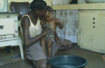 Mother bathing baby daughter inside home.