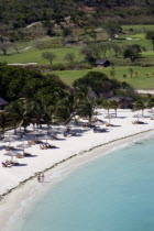 Two women walking along Jambu Beach at Raffles Resort with the Trump International Golf Course behind