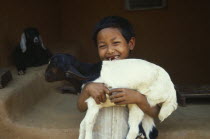 Smiling young child holding lamb.