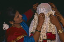 Veiled Moslem bride being garlanded by women