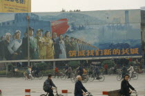 Building our new Great Wall  poster on hoarding beside road with cyclists passing.