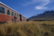 Train stopped on the altiplano at the highest pass on the line between Puno to Cusco with people selling goods to passengers.