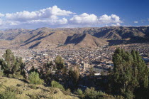 View over trees and the city of Cusco to the mountains beyond.