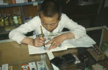 Boy Chinese writing at desk