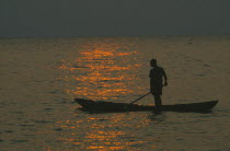 Mokoro canoe raft paddler on water at sunset