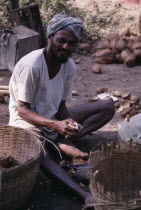 Copra or Coconut Worker sitting with baskets and holding shelled coconut