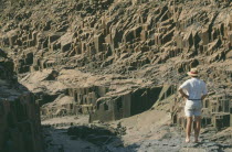 Organ Pipes.Outcrop of volcanic basalt rock in desert . Man standing near rocks