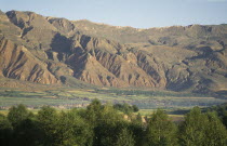 Mountains behind trees and fields at the edge of the Tibetan plateau