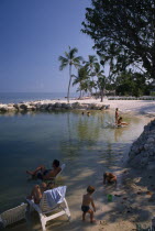 Cheech Lodge Beach with palms  people sitting on sun loungers in the water and children playing in the foreground