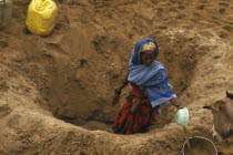 Boran woman digging for water in a dry riverbed