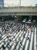 Umeda District Railway Line over a road with traffic under the bridge and a busy pedestrian crossing in the foreground