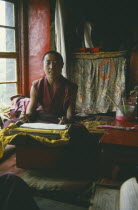 Seated monk in room with prayer book