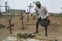 Man cleaning bones at family grave. The bones are removed and washed to make space for the next family member