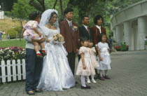 Western style wedding  bride  groom  bridesmaids and family posing for photograph.