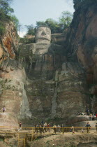 Dafu or Grand Buddha carved into cliff face with visitors behind railings below.