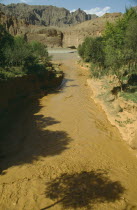 View over rapid flowing silt laden water toward main riverTributary