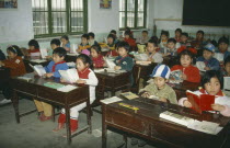 Primary school children reading at desks in classroom.