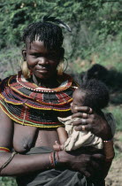 Pokot tribeswoman wearing traditional bead jewellery holding baby.