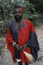 Portrait of traditional priest and healer in village near Accra wearing black and red robes.