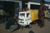 Craftsman painting oil tanker shaped coffin for driver Peter Borkety Kuwono following tradition of decorating coffin to reflect the life of the deceased.