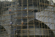 Construction workers on scaffolding surrounding new bank building.West Africa