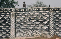 Children on top of outside wall decorated with traditional broken calabash pattern in black and white  symbolic of ever useful. West Africa