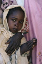 Portrait of Chadian refugee girl standing beside her partly seen mother.