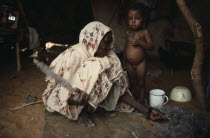 Kababish nomad woman spinning wool inside hut with little girl standing beside her. Kurdufan