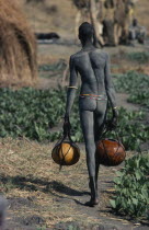 Dinka carrying gourds of water to irrigate crops.