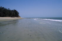 Atlantic Ocean. View along empty stretch of beach with trees growing next to beach