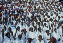 Independence Day Parade. A mass of seated women with their arms raised in the air dressed in white with colourful headscarfes.Colorful African Eastern Africa Somalian Soomaliya Female Woman Girl Lady...