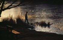 Boy standing on shore of frozen lake testing ice with his foot.Eire Republic Eire Republic Eire Republic Eire Republic Eire Republic